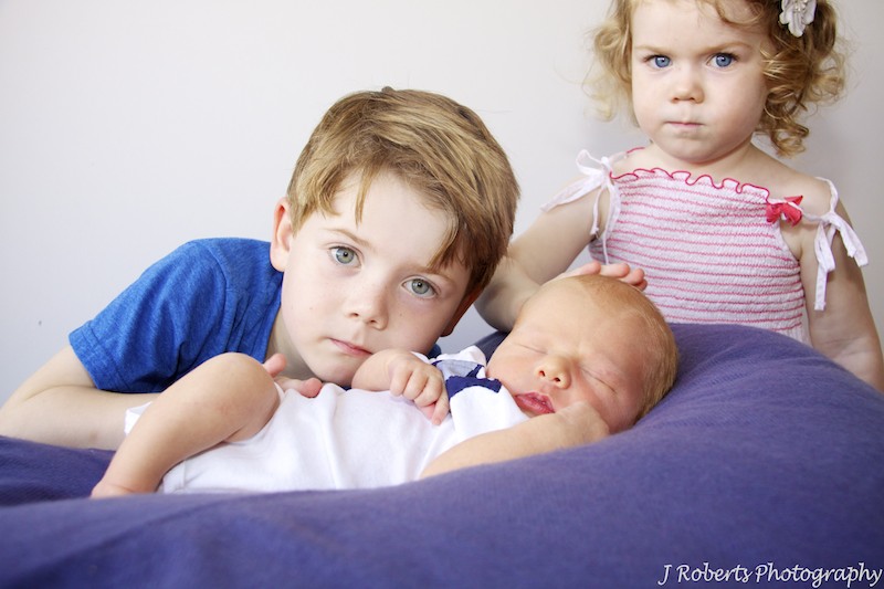 Brother and sister patting newborn brother - newborn portrait photography